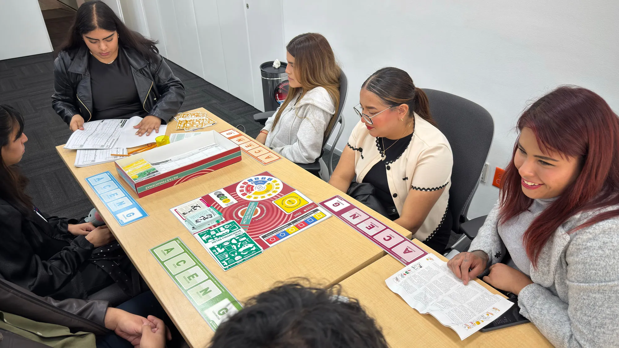 Aprendices jugando “Metas financieras” alrededor de una mesa